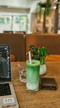 A cozy cafe setup featuring a laptop, matcha latte, and greenery, ideal for freelancers.