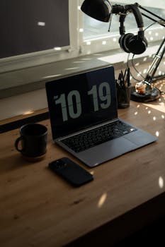 A stylish desk setup featuring a laptop, smartphone, and coffee mug in a sunlit room.