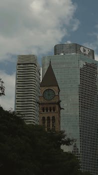 A view of Toronto's Old City Hall clock tower amidst modern skyscrapers showcasing urban contrast.