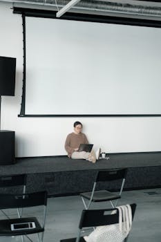 Businesswoman sitting with laptop in empty conference room, embodying focus and modern work culture.