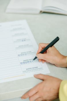 Hands filling out a nutrition plan with a focus on water intake. Ideal for health and wellness themes.