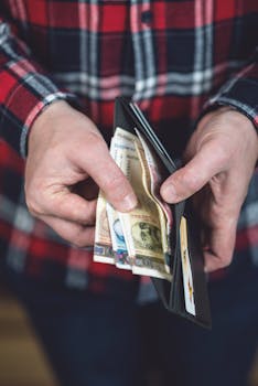 Vertical shot of hands holding a wallet with multiple international currencies, emphasizing global finance.